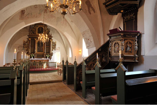 The church interior, with vaulted arches, chandeliers and candles